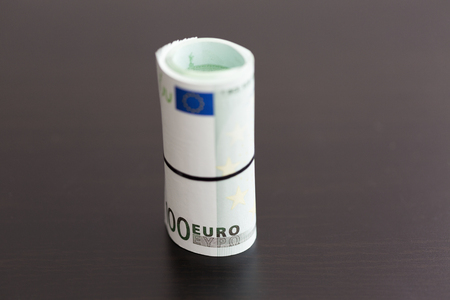 Roll of one hundred euro bills on black backgroundの写真素材