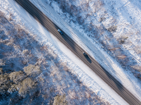 Cars on road in winter with snow covered trees aerial viewの写真素材