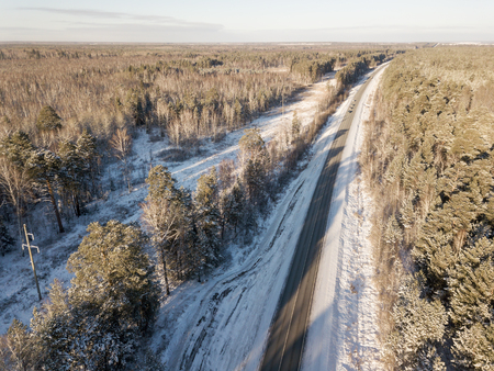 Cars on road in winter with snow covered trees aerial viewの写真素材