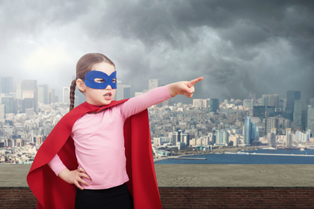 Superhero kid against urban background and gray skyの写真素材