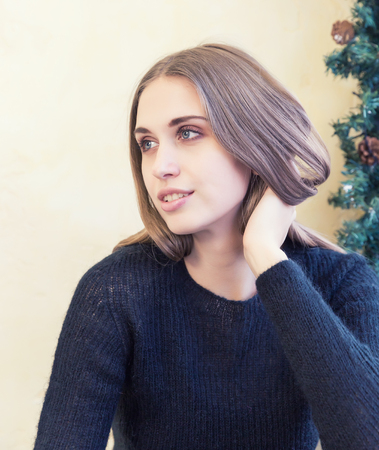 A beautiful young woman in pullover on background of Christmas lightsの写真素材