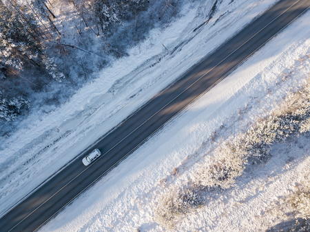 Cars on road in winter with snow covered trees aerial viewの写真素材