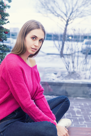 A portrait of beautiful young woman in pullover on background of Christmas lightsの写真素材