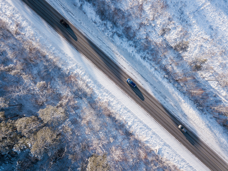 Cars on road in winter with snow covered trees aerial viewの写真素材