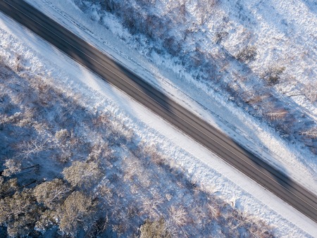 Empty road in winter with snow covered trees aerial viewの写真素材