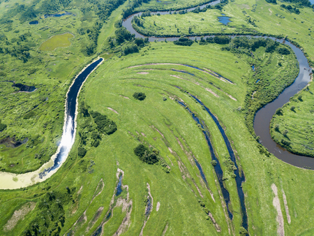 Aerial landscape of winding river in green fieldsの写真素材