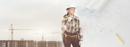 A female construction worker in safety helmet holds a hammer