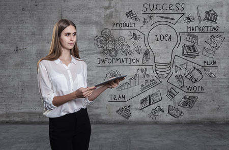 Beautiful business woman against a concrete wall with sketch drawn on itの写真素材