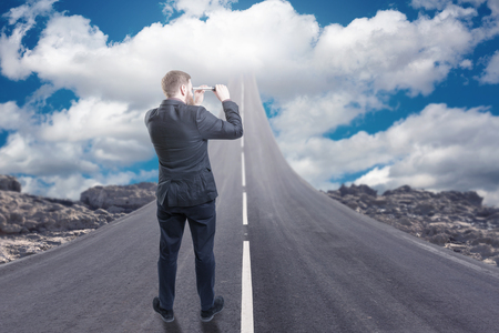 Businessman standing on road that goes up to the skyの写真素材