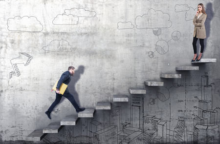 Side view of a businessman climbing the stairs with woman standing on top on a concrete backgroundの写真素材