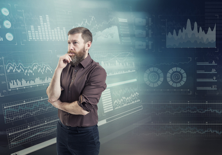 A businessman thinking standing against an abstract financial charts on the backgroundの写真素材