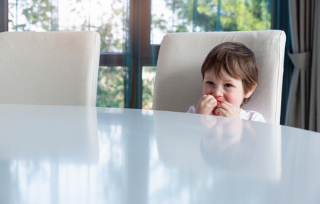 Cute boy eating fresh ripe strawberries at homeの写真素材