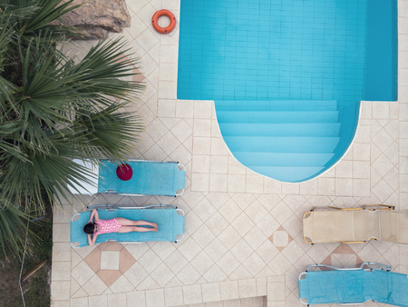 Little girl sunbathing by a swimming poolの写真素材
