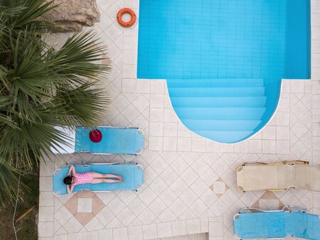 Little girl sunbathing by a swimming poolの写真素材