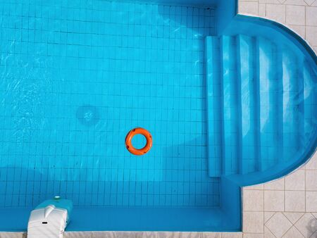 Orange lifebuoy in a swimming pool in summerの写真素材