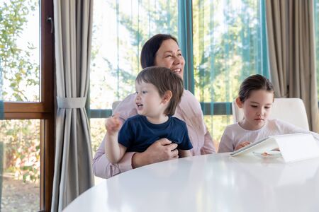 Grandma entertaining her little grandchildren with a tablet computer gameの写真素材