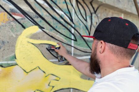 Graffiti artist painting with aerosol spray bottleの写真素材
