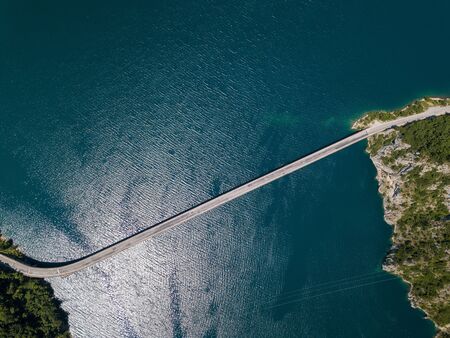 Aerial footage a car driving over a bridge on Piva Lake