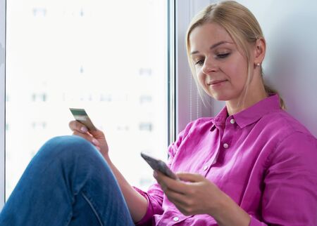Portrait of smiling woman holding credit card in her hand while shopping onlineの写真素材