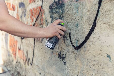 Graffiti Artist hands with paint cans against gray wallの写真素材