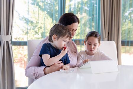 Grandma entertaining her little grandchildren with a tablet computer gameの写真素材