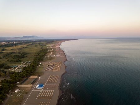 Aerial view of sandy beach with yellow sunbeds and wooden umbrellas at sunsetの写真素材