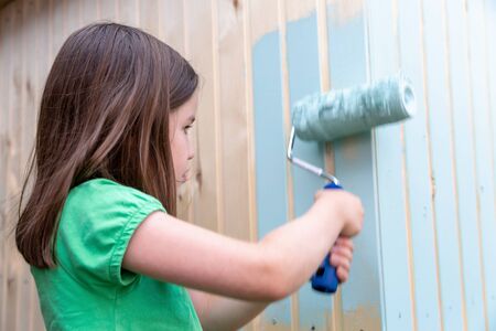 Young girl painting little wooden house with a rollerの写真素材