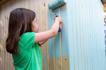 Young girl painting little wooden house with a rollerの写真素材