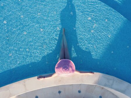 Young woman sunbathing in a swimming poolの写真素材