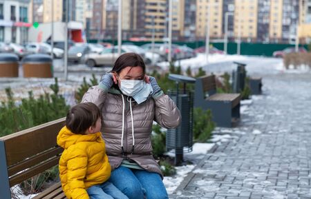 A mother puts protective mask on herself and on her little sonの写真素材