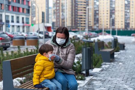 A mother puts protective mask on herself and on her little sonの写真素材