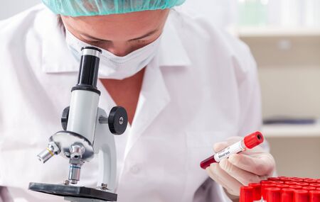 Covid-19 infected blood sample in vacuum tube in hand of scientist doctor in research laboratoryの写真素材