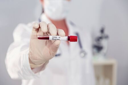 Covid-19 infected blood sample in vacuum tube in hand of scientist doctor in research laboratoryの写真素材