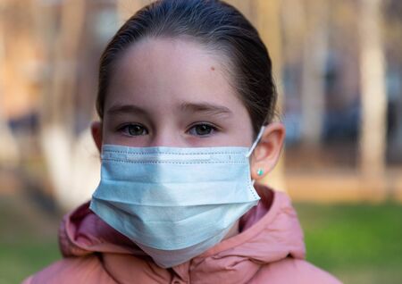 A caucasian girl wearing protective mask walking on a streetの写真素材