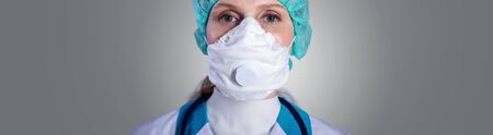 Doctor wearing protection face mask against gray backgroundの写真素材