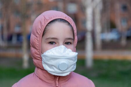 Coronavirus protection. A caucasian girl wearing respirator walking on a streetの写真素材