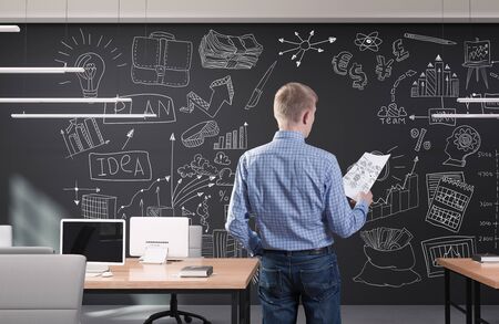 Young businessman in modern office with creative business strategy sketch drawn on a wallの写真素材