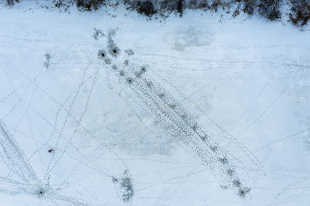 A fisherman fishing in winter time on ice covered riverの写真素材