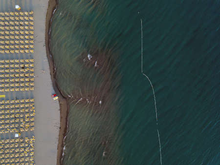 Aerial view of sandy beach with yellow sunbeds and wooden umbrellas at sunsetの写真素材
