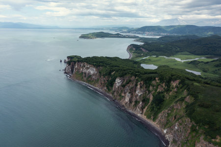 Aerial drone photo of Mayachny Cape on Kamchatka Peninsula on picturesque Avacha bay coast covered by green grass in the Pacific Oceanの写真素材