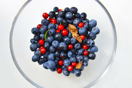 Blueberries and cranberries in a glass dish on a white background. Autumn berries are rich in...