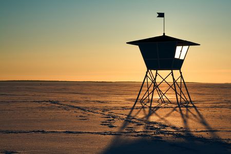 Life-guard's hut during sunset in winter with frozen seaの写真素材