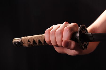 Closeup of man holding samurai sword in dramatic studio lightの写真素材