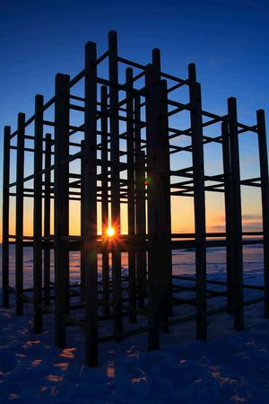 Sunset on frozen sea shore with playground silhouette