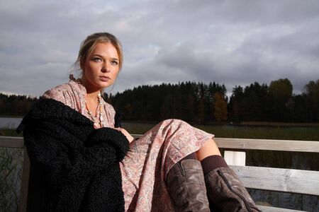 Young woman in retro clothing on a lakeshore in Finlandの写真素材