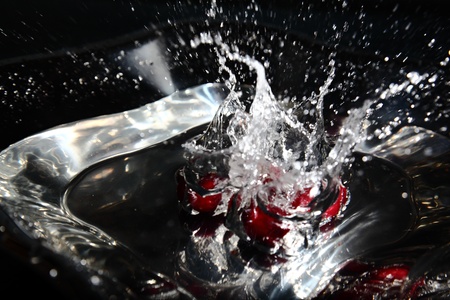 Shiny water splash with cherry falling in the waterの写真素材