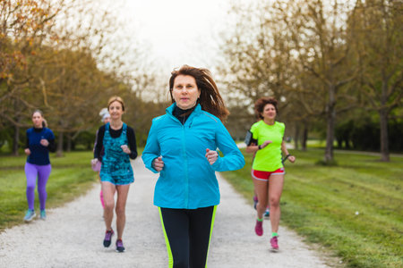 Mature lady leading a group of female runners training in nature. Concept of physical fitness also in the old age.の写真素材