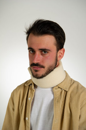 close up portrait of a young man wearing a beige neck protector. neck support for safety with white...