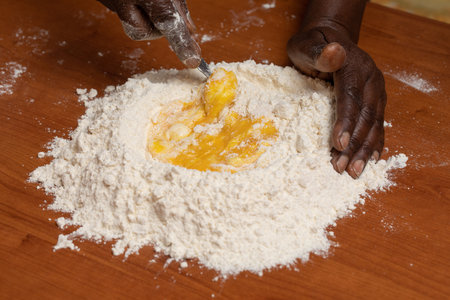 Black african person hands mix egg and flour on kitchen top table prepare meal indoorsの写真素材