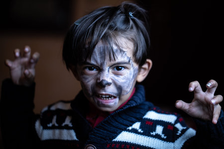 Child disguised as a werewolf during Halloween. Threatening face while showing jaws and claws, on...
